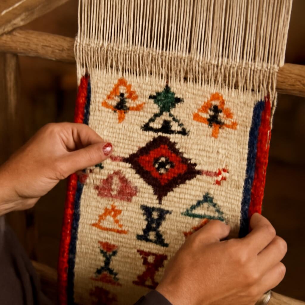 Femme berbère tissant un kilim amazigh sur métier à tisser traditionnel, symboles tissés à la main